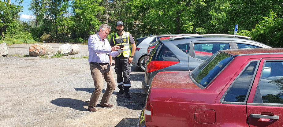 två män framför parkerade bilar